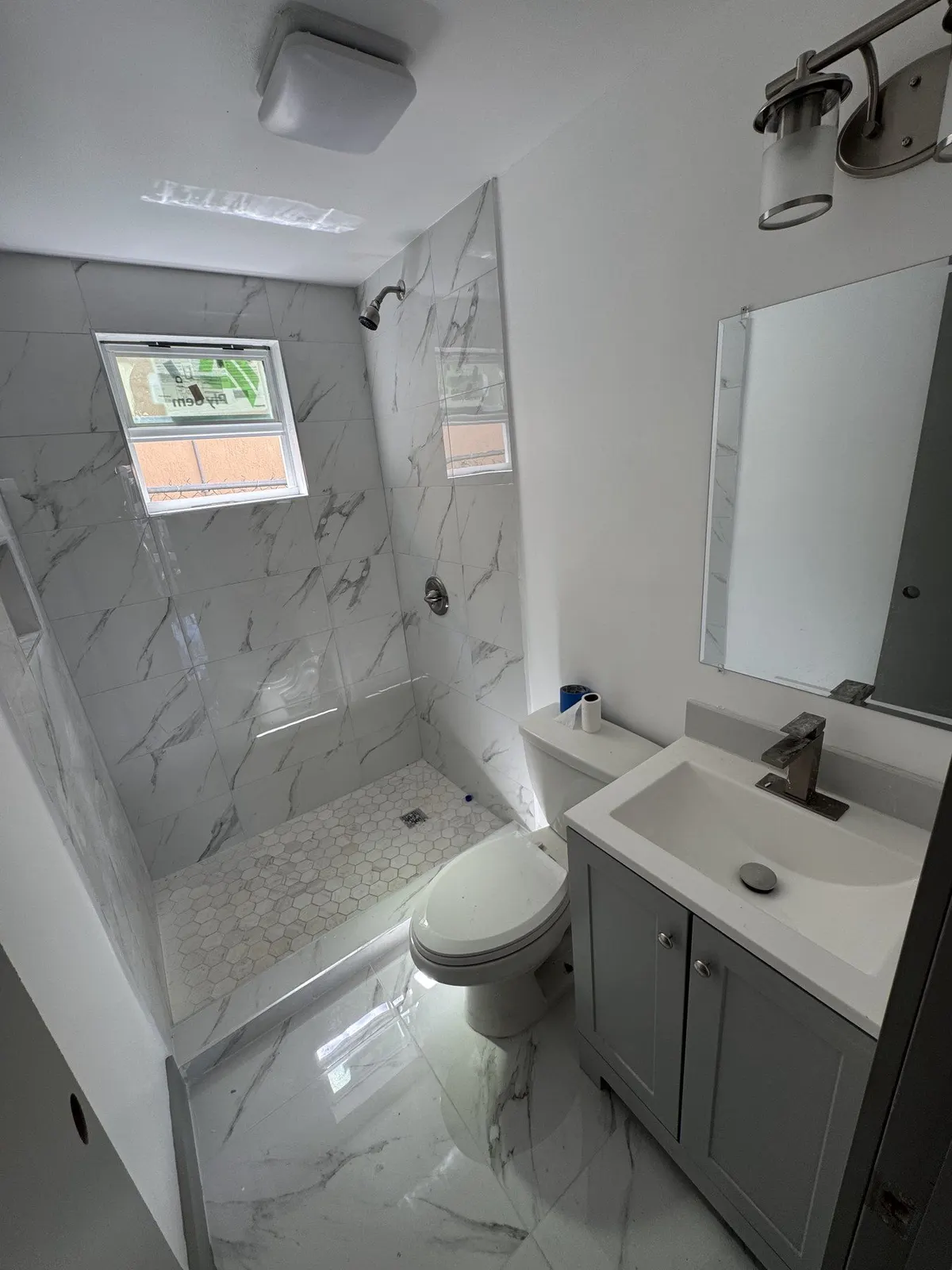 Bright bathroom with white vanity and marble-look tiled shower.