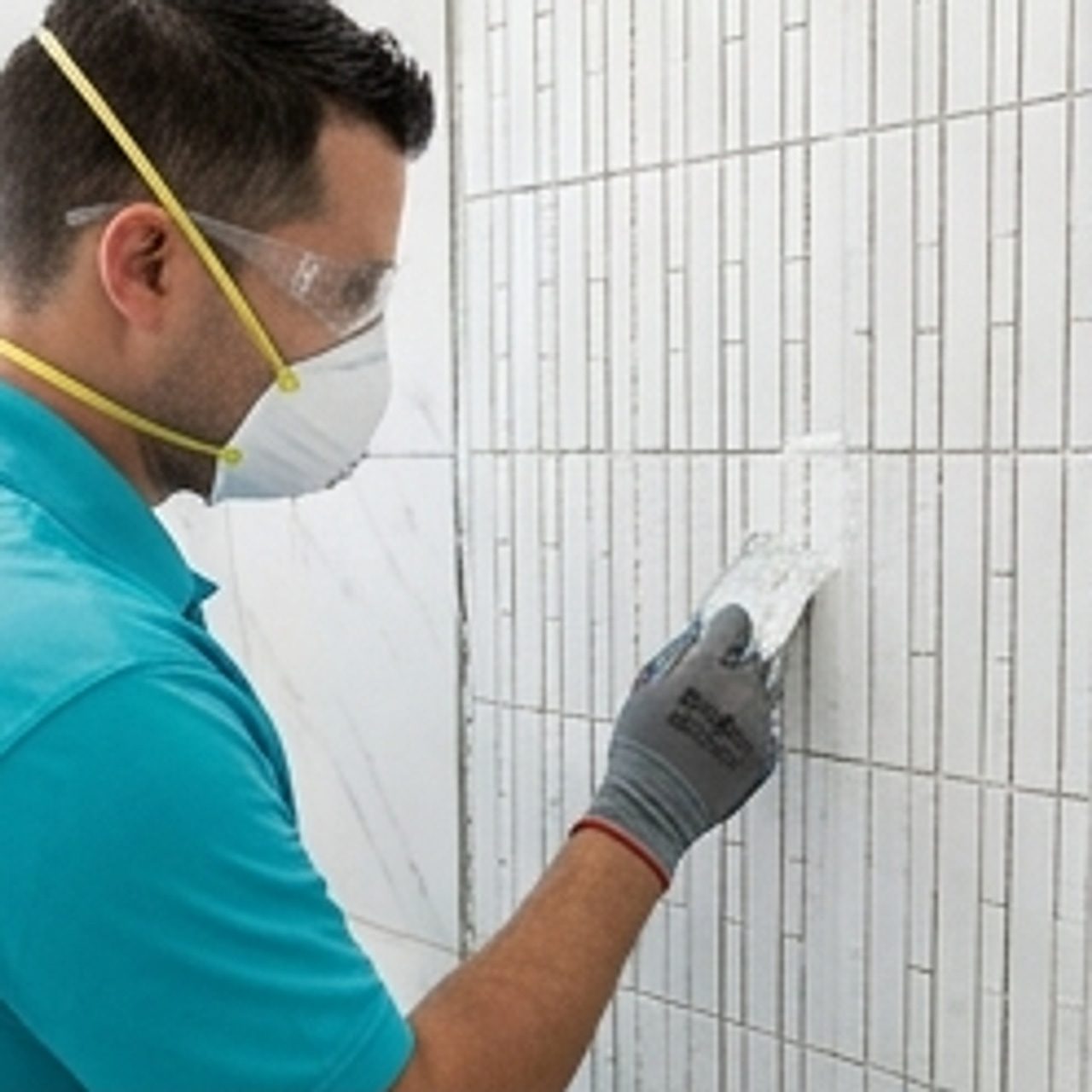 worker applying grout to shower tiles