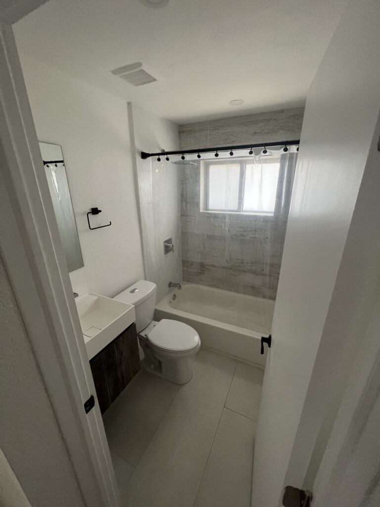 Bathroom with bathtub, tiled walls, and frosted window above tub.