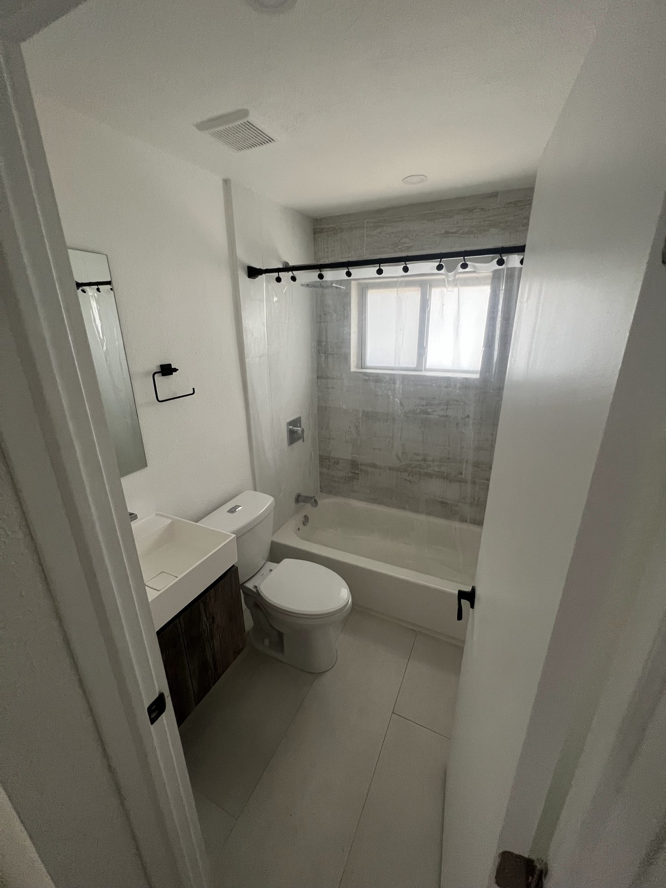 Bathroom with bathtub, tiled walls, and frosted window above tub.