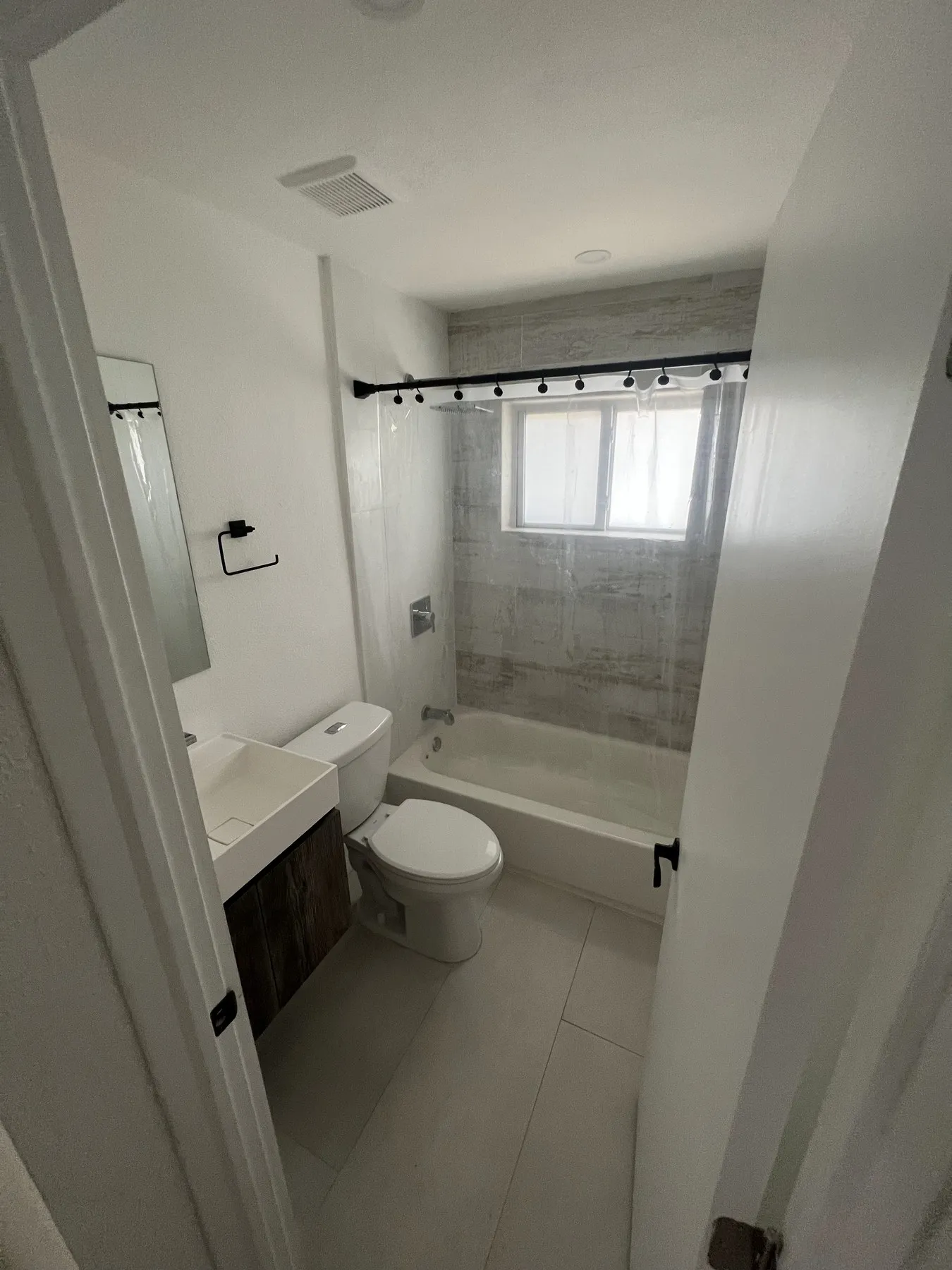 Bathroom with bathtub, tiled walls, and frosted window above tub.