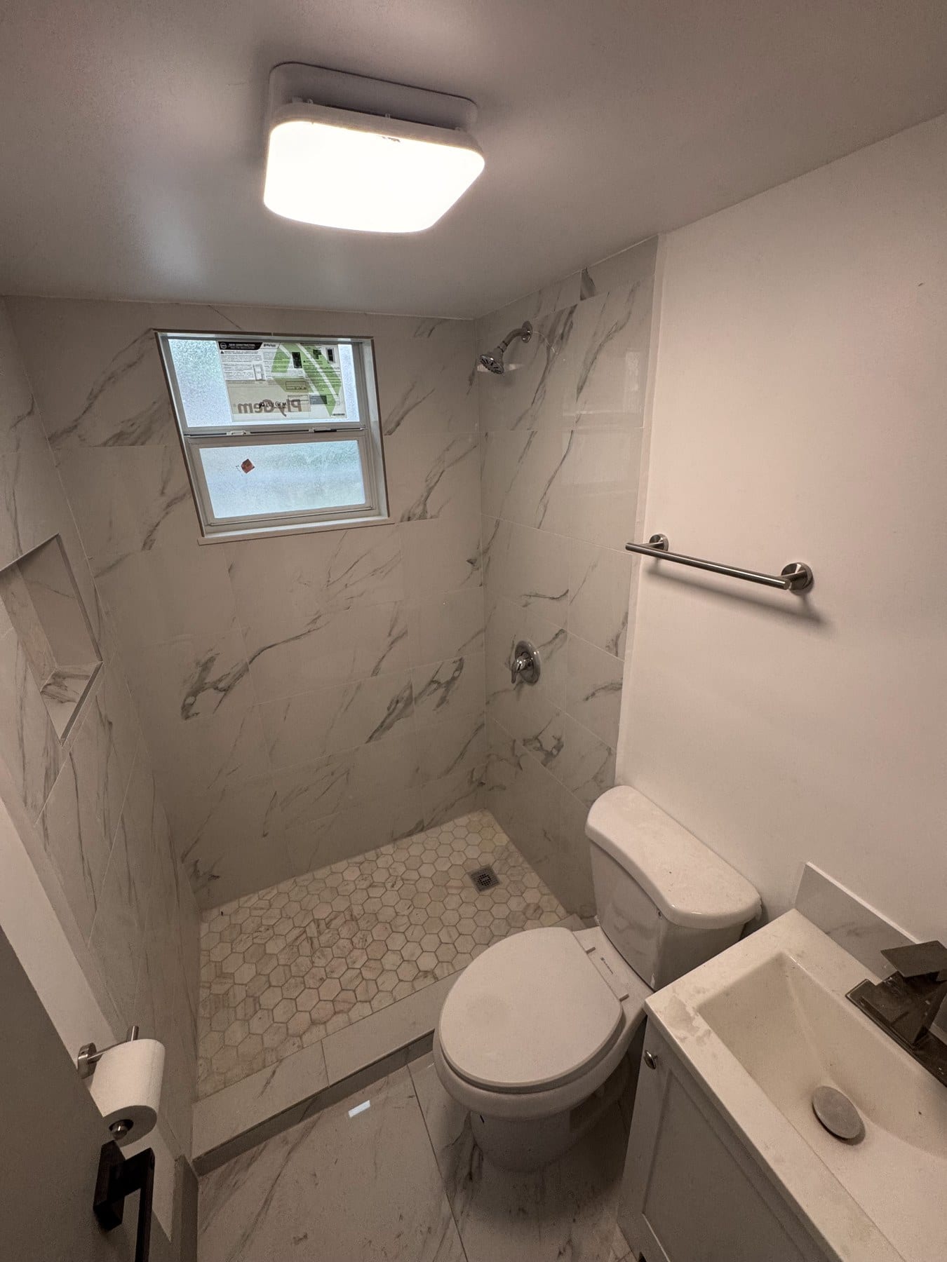 Small bathroom with pebble shower floor and toilet beside it.