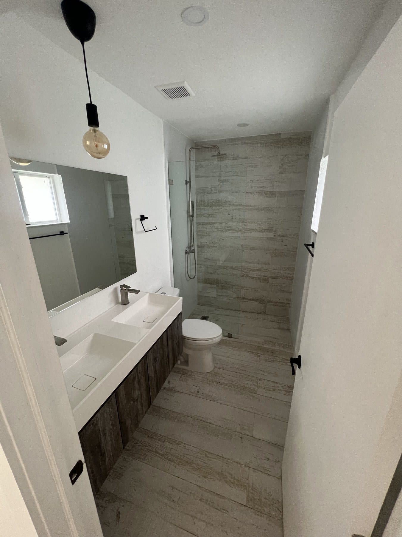 Long vanity with single sink, pendant light, and wood-look floor.