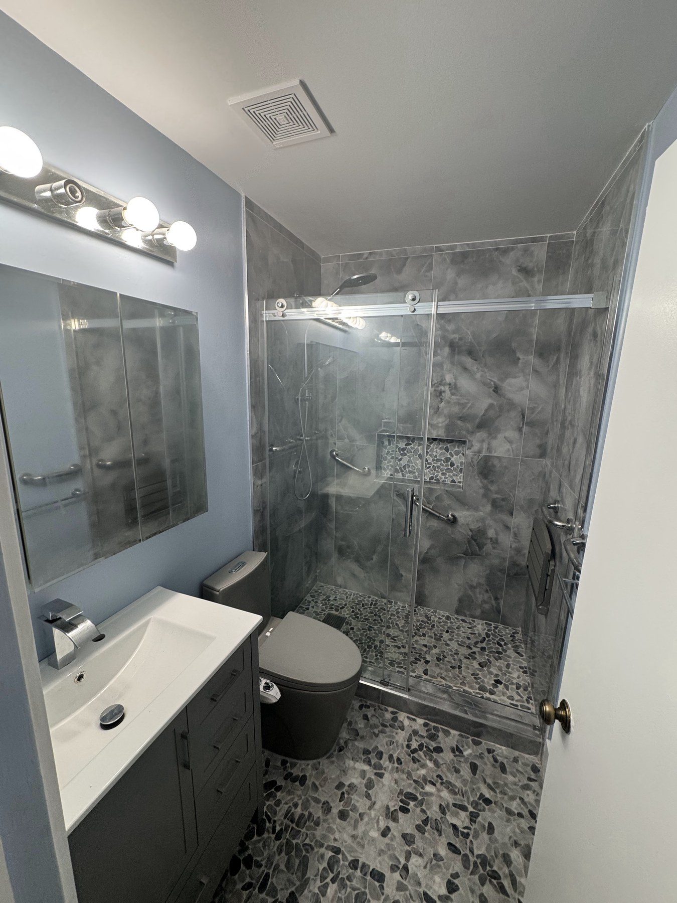 Modern bathroom with glass-enclosed shower and marble-look wall tile.