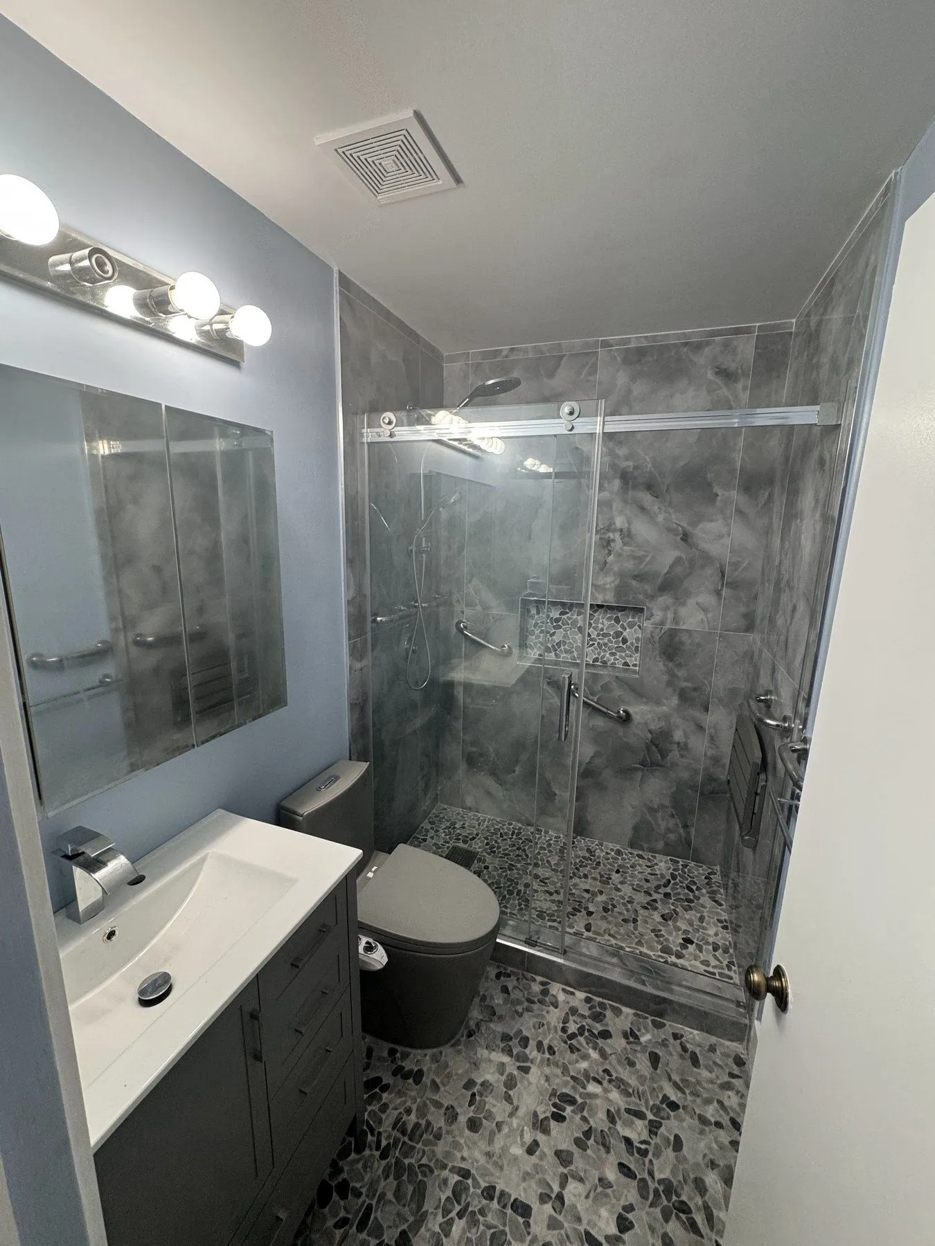 Modern bathroom with glass-enclosed shower and marble-look wall tile.