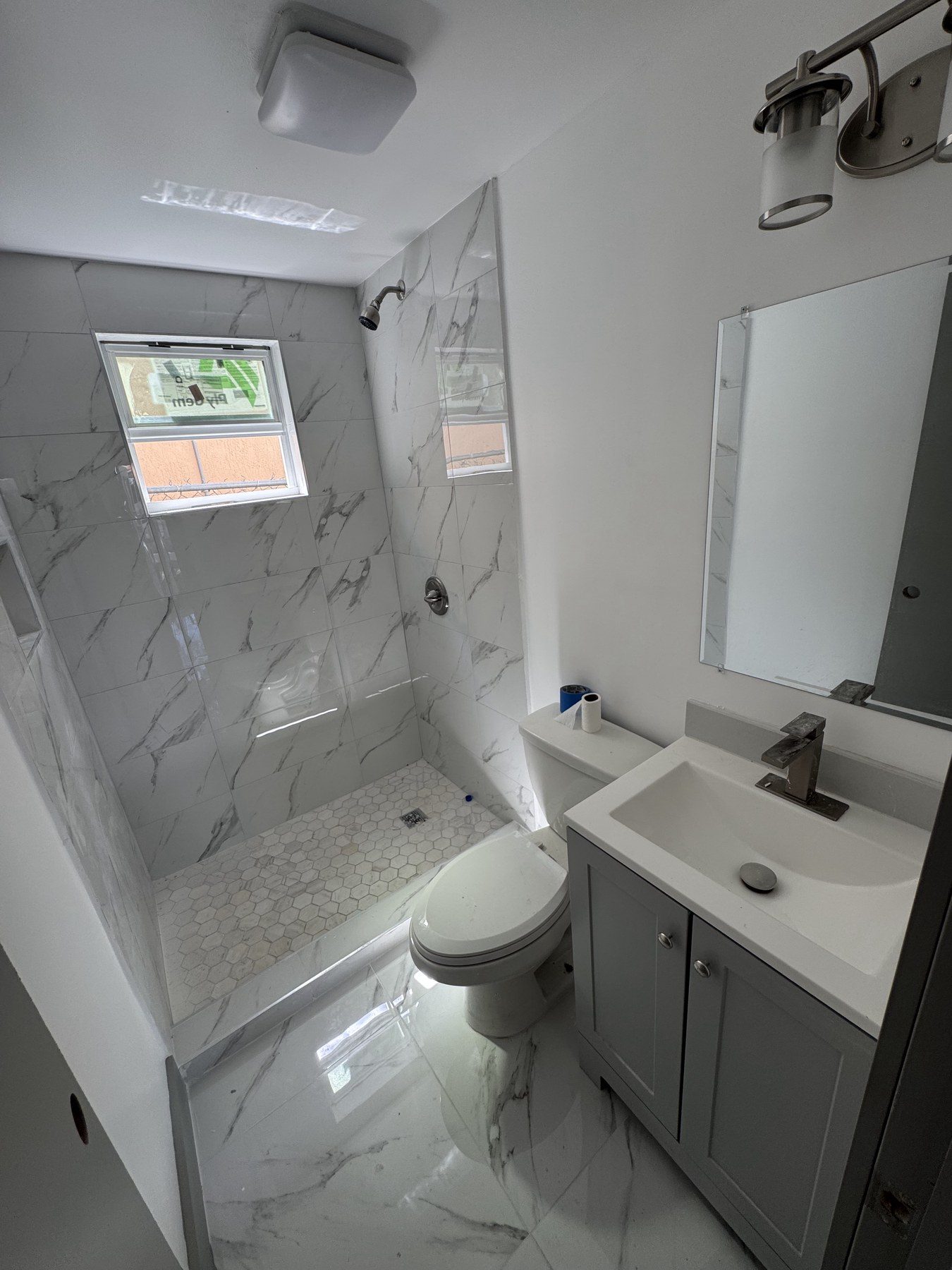 Bright bathroom with white vanity and marble-look tiled shower.