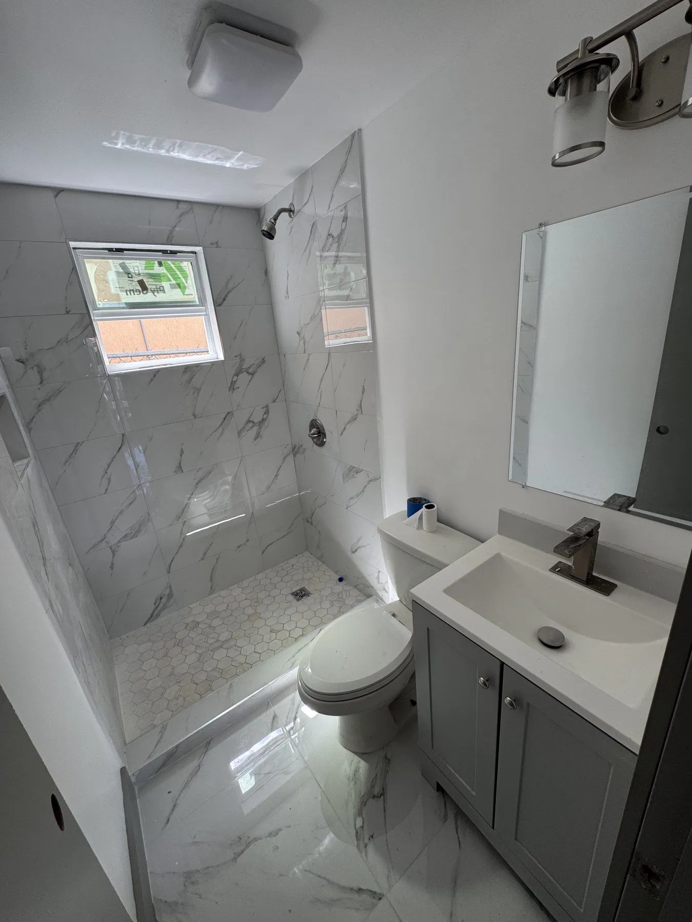 Bright bathroom with white vanity and marble-look tiled shower.